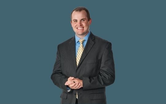 Smiling man in a blazer appears on a dark teal background. Text below reads "Kyle Boardman, CPA, CFP, Principal"
