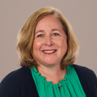 Woman with short blonde hair and a black cardigan smiles on a white background