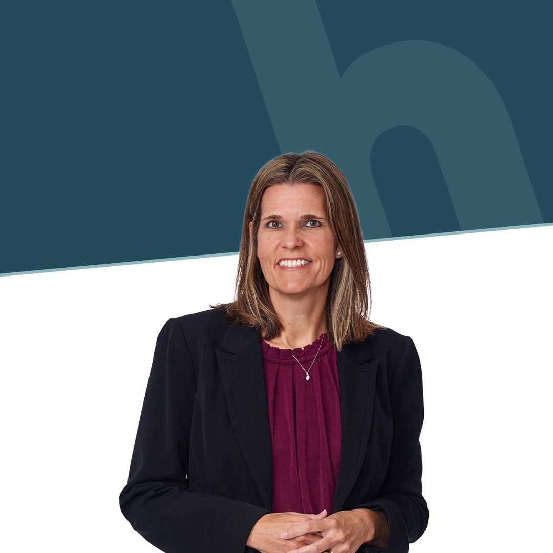 Brunette woman in a black blazer smiles in front of a white and green background with the Honkamp logo