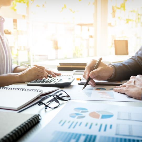 In front of a bright window, two people review charts at a table