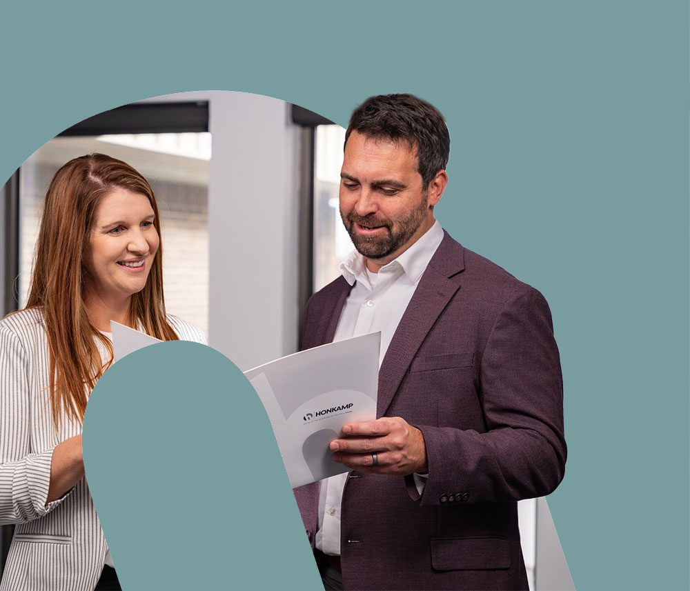 In a cutout of the Honkamp logo, a man and woman look at a Honkamp branded folder