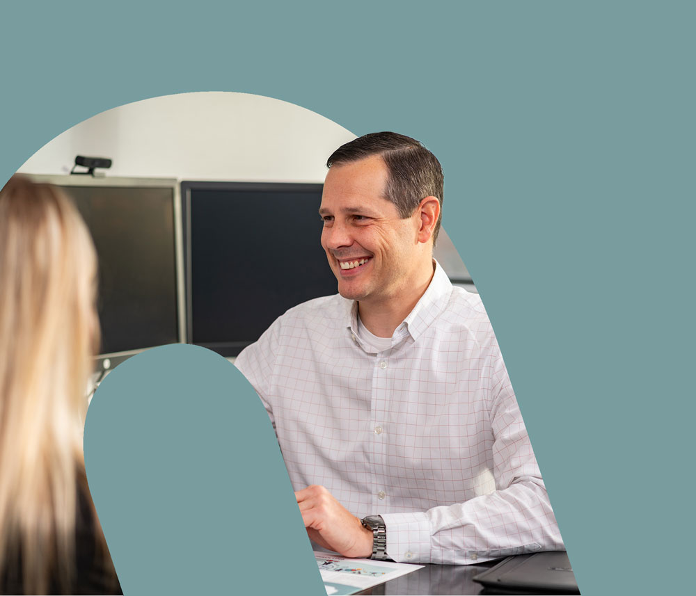 In a cutout of the Honkamp logo, a man in a button down smiles at a woman obscured in the foreground