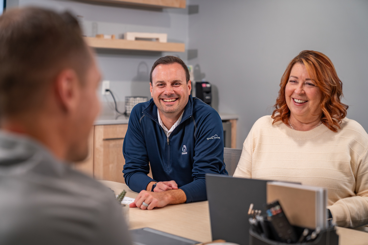 Seated man and woman laugh together while talking to a man with his back to the camera