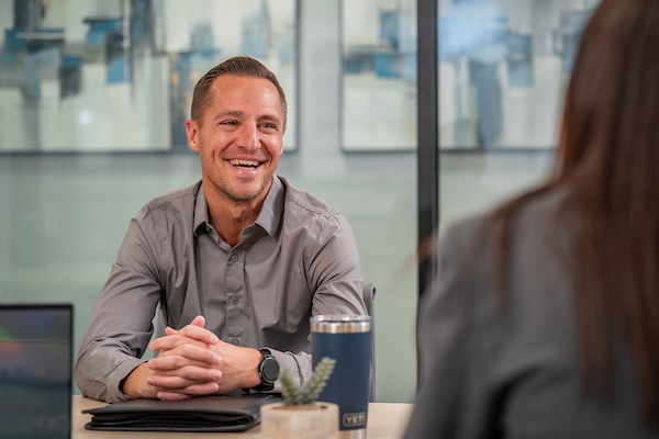 A man laughs in front of a glass wall in a conference room