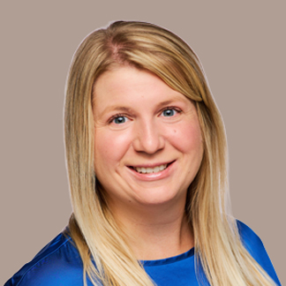 Blonde woman in a blue blouse smiles on a tan background